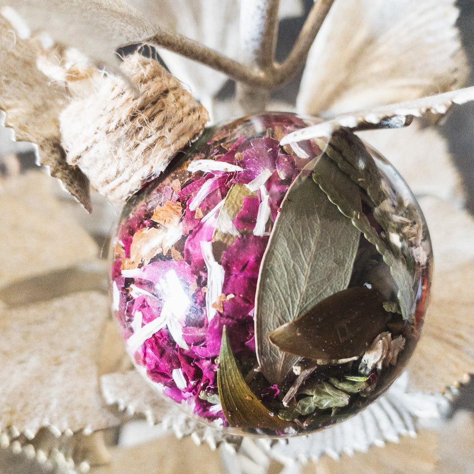 Glass ornament containing dried eucalyptus leaves and pink rose petals. Handmade and shop local Calgary.