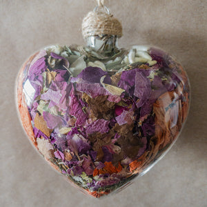 Large (3.5 inches wide by 4 inches tall) glass heart filled with dried orange lilies, pink rose petals, baby's breath and devil's ivy flower.