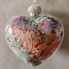 Load image into Gallery viewer, Large (3.5 inches wide by 4 inches tall) glass heart filled with dried orange lilies, pink rose petals, baby&#39;s breath and devil&#39;s ivy flower.
