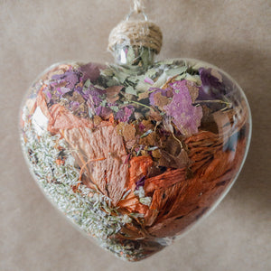 Large (3.5 inches wide by 4 inches tall) glass heart filled with dried orange lilies, pink rose petals, baby's breath and devil's ivy flower.