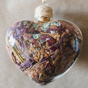 Large (3.5" wide x 4" tall) glass heart filled with rose gold lilies, red rose petals and blue hydrangeas.