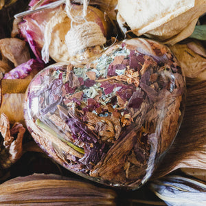 Large (3.5" wide x 4" tall) glass heart filled with rose gold lilies, red rose petals and blue hydrangeas.