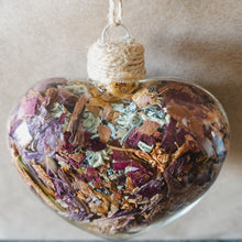 Load image into Gallery viewer, Top view of a glass heart filled with rose gold lilies, red rose petals and blue hydrangeas.
